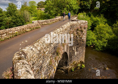 Royaume-uni, Angleterre, Devon, Staverton, deux hommes marcheurs crossing vieux pont de pierre sur la rivière Dart Banque D'Images