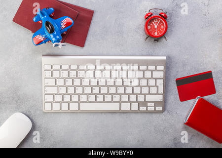 Avion avec près de passeports de payer par carte de crédit et le clavier. Réservation de billets en ligne concept. Un gain de temps. Horloge rouge, fond gris. Banque D'Images