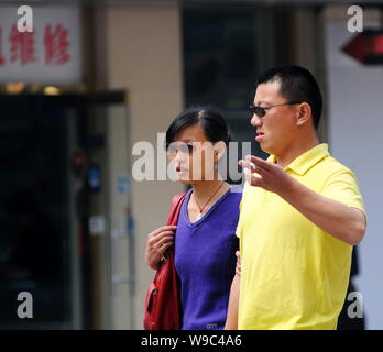 --FILE--un Chinois fume en marchant avec une femme dans une rue de Beijing, Chine, 15 avril 2008. Liu Zejun, le directeur de l'Aiguo Beijing nous Banque D'Images