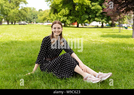 Belle jeune femme est assise sur l'herbe. Concert d'été fraîches et naturelles. Banque D'Images