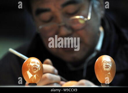 Sculpteur folk chinois Kang Yongguo est vu sculpture d'un oeuf de poule derrière deux œufs sculptés avec les portraits du président chinois Hu Jintao, droite, et Banque D'Images