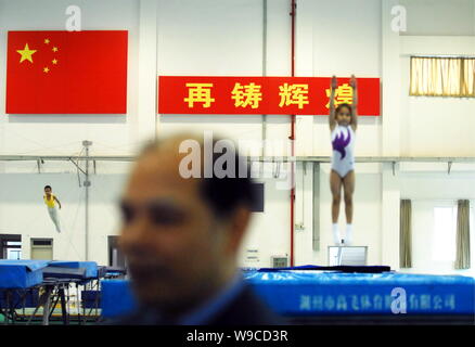 Peu d'athlètes chinois exercice trampoline devant un drapeau national chinois et signes sens pour faire un grand succès de nouveau pendant une sessio formation Banque D'Images