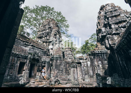 Caucasian man with camera debout parmi les ruines du temple d'Angkor Wat à Siem Reap, Cambodge. Banque D'Images