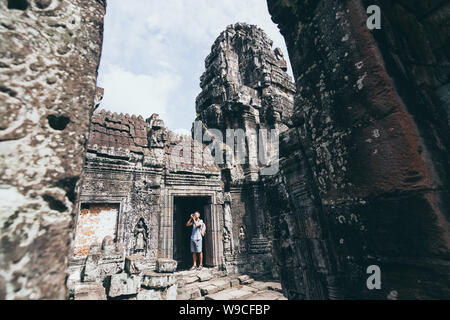 Caucasian man with camera debout parmi les ruines du temple d'Angkor Wat à Siem Reap, Cambodge. Banque D'Images