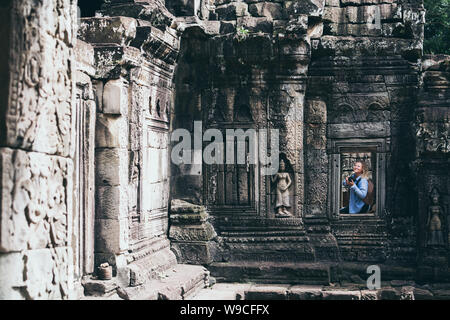 Young blonde woman prendre des photos d'Angkor Wat temple complexe ruines à Siem Reap, Cambodge. Banque D'Images