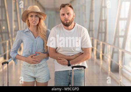 Couple souffrant de l'estomac, arrivant à l'aéroport Banque D'Images