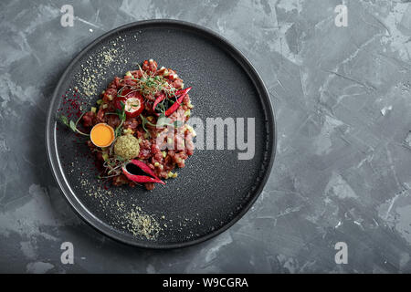 Tartare de boeuf d'oeuf sur une surface grise, vue de dessus, close-up copy space Banque D'Images