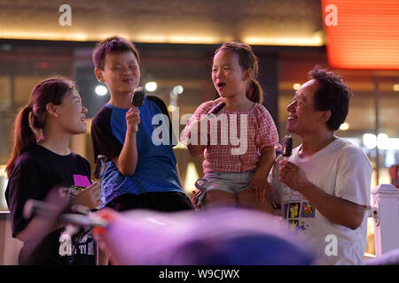 (190813) -- NANCHANG, le 13 août 2019 (Xinhua) -- Tan Hongbo et sa famille mangent les sucettes glacées au cours de shopping à Qingshanhu District, Guangzhou City, province de Jiangxi, Chine orientale, le 12 août 2019. Tan Hongbo, 39 ans, et sa femme Wang Yuanzhen, 34, sont des travailleurs migrants dans la région de Nanchang. Ils ont laissé leur fils et fille Tan Tan Zheng Jinxin avec les grands-parents dans la région de Duchang Comté de Jiujiang Ville. Lors des vacances d'été, les enfants en sont venus à Nanchang pour rejoindre leurs parents. Tan Hongbo couple a décidé de transférer leurs enfants à Nanchang pour aller à l'école l'année prochaine, le ministère de l'éducation de Qingshanhu District Banque D'Images