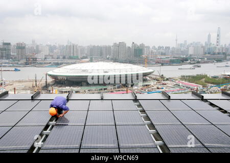 Un travailleur chinois installe des panneaux solaires sur le toit du pavillon de la Chine à l'Exposition Universelle de Shanghai place à Shanghai, Chine, 1 septembre 2009. Énergie corr Banque D'Images