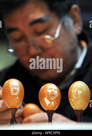 Sculpteur folk chinois Kang Yongguo est vu sculpture d'un oeuf de poule derrière trois oeufs sculptés avec les portraits de (de gauche) Le président chinois Hu Jinta Banque D'Images