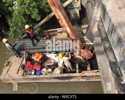 SAMUT PRAKAN, THAÏLANDE, NOV 24 2018,Équipe de travailleurs tirez des colonnes de béton hors de l'eau sur le fer avec ponton grue. Reconstruire la côte de la rivière Banque D'Images