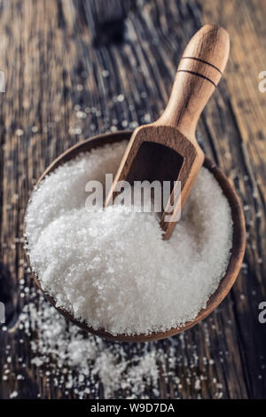 Gros grain de sel dans un bol en bois avec une louche sur une vieille table en chêne Banque D'Images