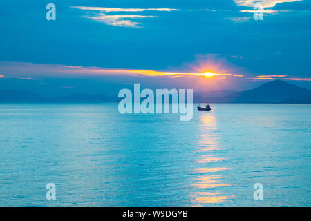 Bateau de pêche en mer sur les feux de coucher du soleil à Sanya, Hainan, China Banque D'Images