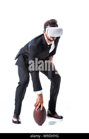 En homme d'usure formelle et casque de réalité virtuelle avec ballon de rugby sur blanc Banque D'Images