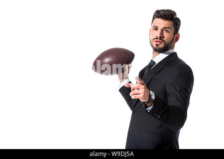Homme d'affaires en tenue de cérémonie avec ballon de rugby pointant avec le doigt Isolated On White Banque D'Images