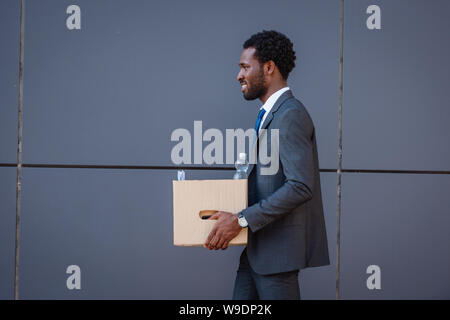 Vue latérale du beau african american businessman holding cardboard box Banque D'Images