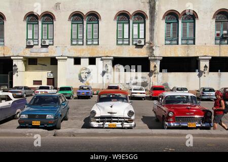 La HAVANE, CUBA - 30 janvier 2011 : les gens marchent par classic voitures américaines à La Havane. Cuba a l'un des taux de location par habitant élevés (38 pour 1000 personnes je Banque D'Images