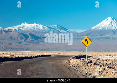 La courbe de la route avec panneau jaune au milieu de désert d'Atacama montrant Road tournez à l'avant Banque D'Images