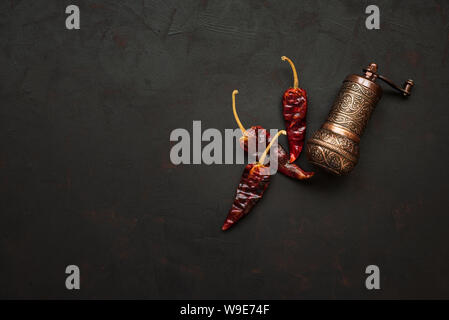 Moulin à poivre turc ou meules avec des grains de poivre de Red Hot Chili Peppers sur fond de bois sombre. Vue d'en haut. Copier l'espace. Concept d'aliments sains Banque D'Images