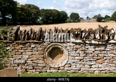 Une vieille pierre dans le mur de Saint Mary's churchyard, Warkworth, Northamptonshire, England, UK Banque D'Images