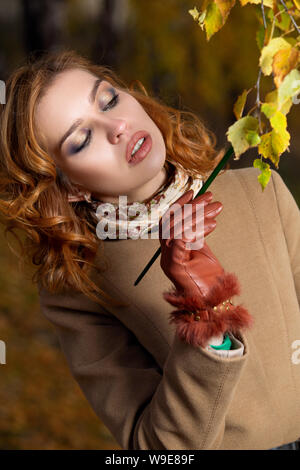 Belle femme avec pinceau et palette de couleurs peintures feuilles des arbres Banque D'Images