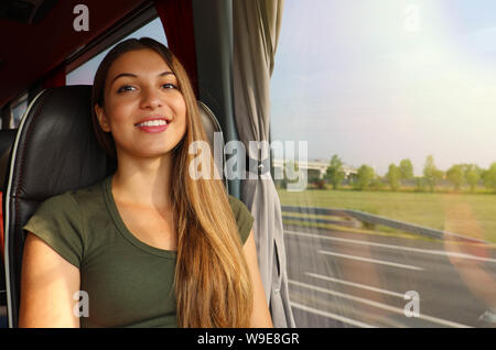 Smiling girl voyager en bus avec la sortie de la fenêtre regardant la caméra Banque D'Images