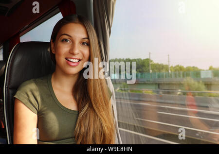 Smiling girl voyager en bus avec la sortie de la fenêtre regardant la caméra Banque D'Images