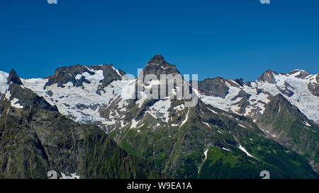 Des pics de montagne avec un glacier et le début d'un torrent de montagne qui traverse une forêt de pins. Nord du Caucase, Russie Banque D'Images