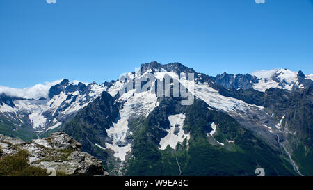 Des pics de montagne avec un glacier et le début d'un torrent de montagne qui traverse une forêt de pins. Nord du Caucase, Russie Banque D'Images