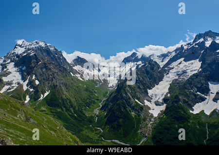 Des pics de montagne avec un glacier et le début d'un torrent de montagne qui traverse une forêt de pins. Nord du Caucase, Russie Banque D'Images