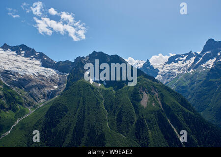 Des pics de montagne avec un glacier et le début d'un torrent de montagne qui traverse une forêt de pins. Nord du Caucase, Russie Banque D'Images