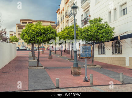 Nerja, Malaga, Espagne - 20 mars 2019 : rue piétonne avec pavage rouge et des rangées d'arbres flanquée de maisons aux façades blanches Banque D'Images