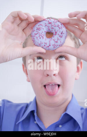 Peu de professionnels cute boy eating donut blanc est le seul fond de cuisine Banque D'Images