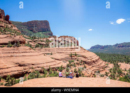 Sedona Arizona USA. Le 25 mai 2019. Groupe de jeunes randonneurs assis sur un terrain à la recherche au niveau de la vue. Orange Rouge paysage désertique, ciel bleu clair, ensoleillé sp Banque D'Images