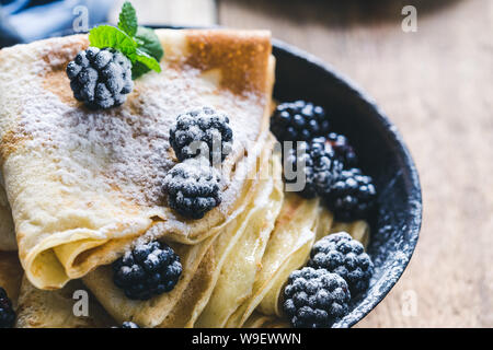 Petit-déjeuner sain ou le brunch, repas du matin préféré. Des crêpes faites maison, l'été frais Fruits blackberry de sucre glace en milieu rural le moule sur une table en bois, cl Banque D'Images