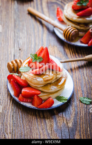 Petit-déjeuner sain ou le brunch, repas du matin préféré. Crêpes maison, l'été frais fraises avec du sucre en poudre, le miel sur table en bois en milieu rural, cl Banque D'Images