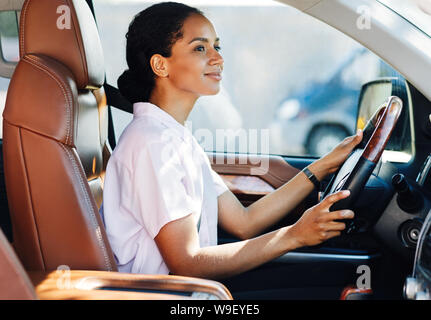 Certain jeune femme au volant voiture. Vue de côté de femme tenant un volant. Banque D'Images