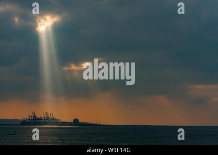 Taipei, Taiwan. 29 Nov, 2009. Rayons crépusculaires, la lumière du soleil d'eau par de petits trous dans les nuages au-dessus du terminal à conteneurs du port de Taipei à l'orifice de Taipei dans le quartier de Bali, comme vu de Tamsui District, Taipei, Taiwan. Banque D'Images