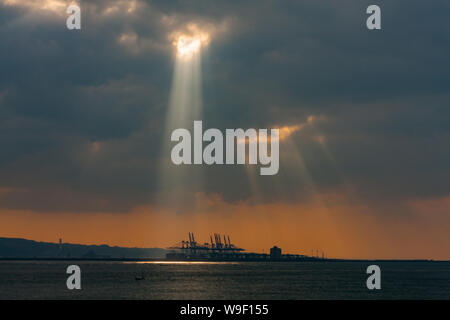 Taipei, Taiwan. 29 Nov, 2009. Rayons crépusculaires, la lumière du soleil d'eau par de petits trous dans les nuages au-dessus du terminal à conteneurs du port de Taipei à l'orifice de Taipei dans le quartier de Bali, comme vu de Tamsui District, Taipei, Taiwan. Banque D'Images