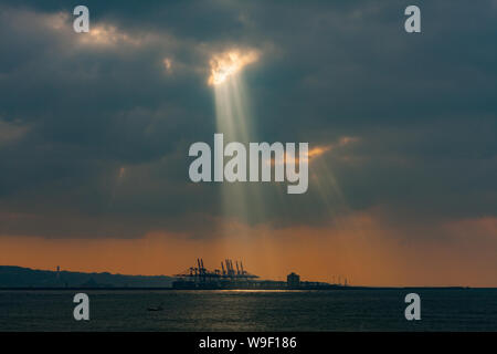 Taipei, Taiwan. 29 Nov, 2009. Rayons crépusculaires, la lumière du soleil d'eau par de petits trous dans les nuages au-dessus du terminal à conteneurs du port de Taipei à l'orifice de Taipei dans le quartier de Bali, comme vu de Tamsui District, Taipei, Taiwan. Banque D'Images
