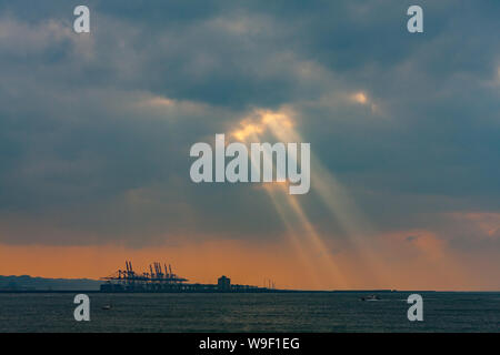 Taipei, Taiwan. 29 Nov, 2009. Rayons crépusculaires, la lumière du soleil d'eau par de petits trous dans les nuages au-dessus du terminal à conteneurs du port de Taipei à l'orifice de Taipei dans le quartier de Bali, comme vu de Tamsui District, Taipei, Taiwan. Banque D'Images