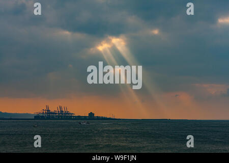 Taipei, Taiwan. 29 Nov, 2009. Rayons crépusculaires, la lumière du soleil d'eau par de petits trous dans les nuages au-dessus du terminal à conteneurs du port de Taipei à l'orifice de Taipei dans le quartier de Bali, comme vu de Tamsui District, Taipei, Taiwan. Banque D'Images
