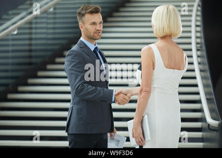 Young Woman in suit standing and shaking hands with young businesswoman avant la réunion Banque D'Images