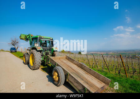 Alsace, France - Apr 19, 2019 - Vue arrière de l'excavatrice John Deere 6100 tracteur avec remorque stationnée à vineyard Banque D'Images