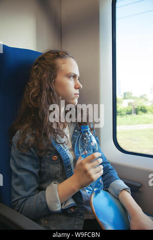 Teen girl monte un train avec un skateboard dans ses mains Banque D'Images