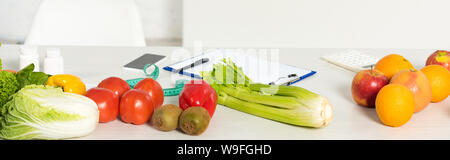 Vue panoramique tourné de fruits et légumes frais, mesurer la bande, presse-papier, stylo, calculatrice et smartphone avec écran vide sur le tableau Banque D'Images