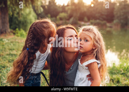 Mère et ses filles accolades et embrassades à l'extérieur. Balades Familiales d'été par river au coucher du soleil. Journée internationale de Childrens Banque D'Images
