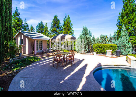 Pool house avec table, chaises et parasol à côté Piscine Banque D'Images