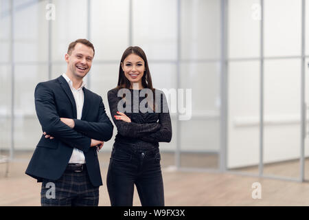 Un homme d'affaires et femme debout dos à dos avec des sourires sur leurs visages Banque D'Images