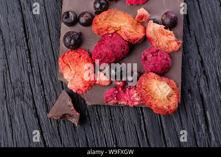 Chocolat artisanal bar avec baies séchées sur un tableau noir en bois. Un plan macro. Vue d'en haut Banque D'Images